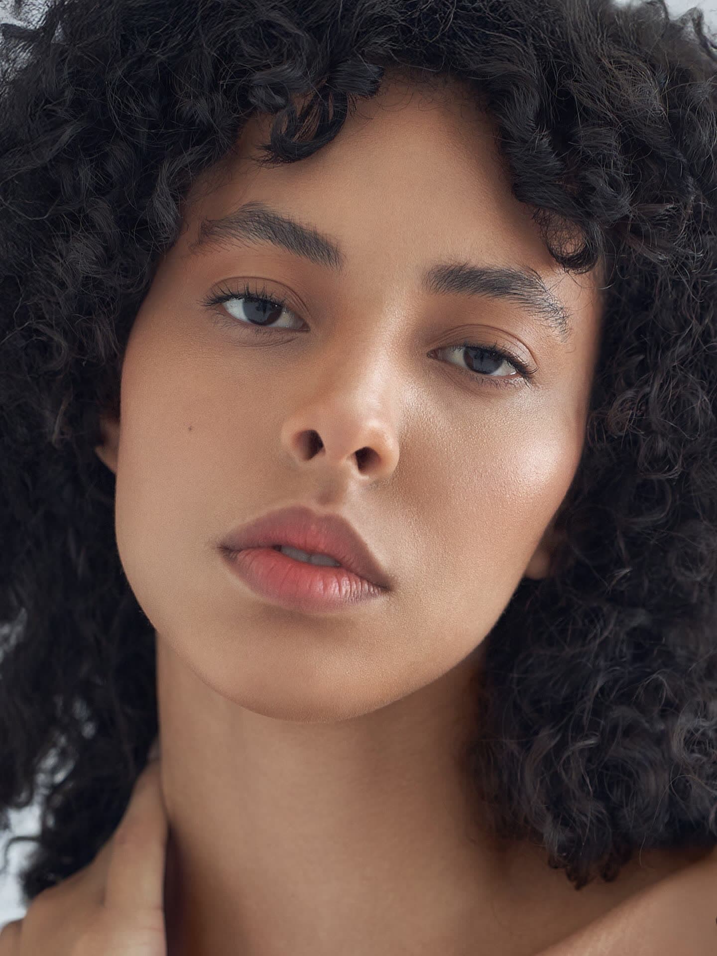 Test frame: tight beauty crop on the face, natural curls framing, direct gaze