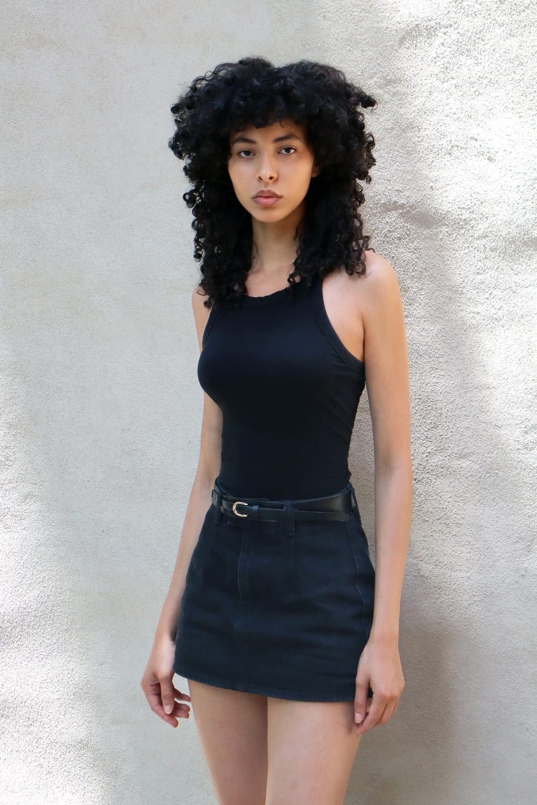 Digital: full length in black mini skirt against white wall