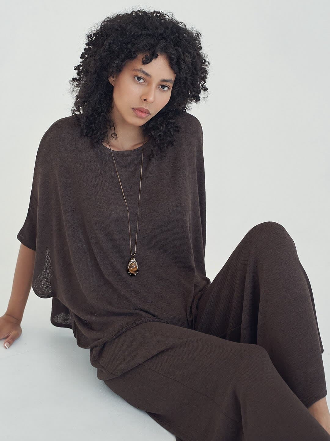 Test frame: Jess seated on the floor with legs extended, mocha knit set