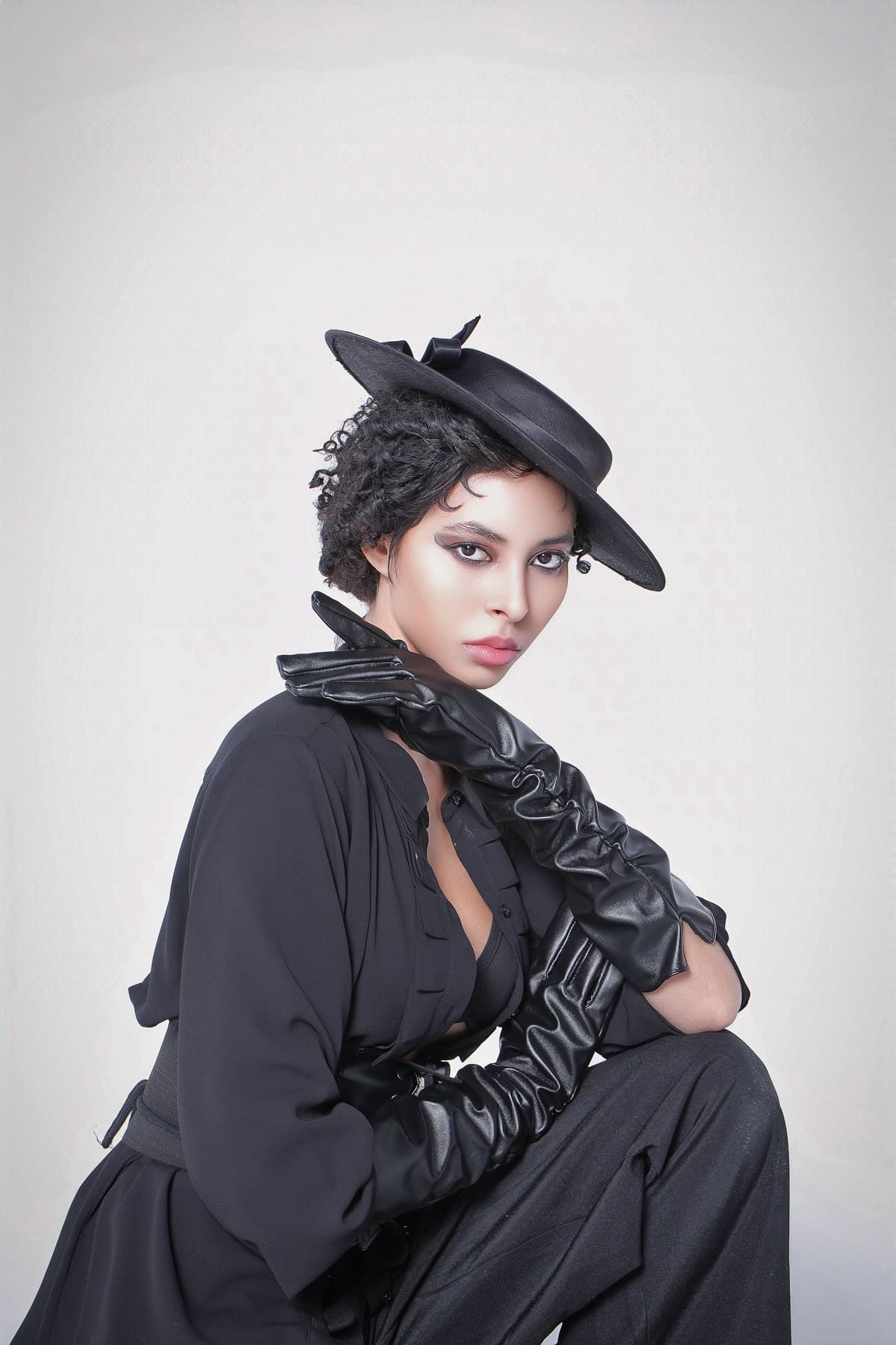 Jess in a black leather corset belt and boater hat, from her GOJI magazine editorial